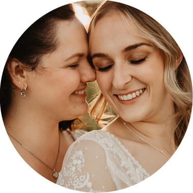 Zwei queere Bräute kuscheln beim Paarshooting ihrer LGBTQ+ Hochzeit miteinander, während die Hochzeitsfotografin den Moment verewigt.