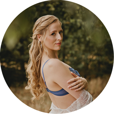 Michelle schaut beim Boudoirshooting in der Natur mit sinnlichem Blick in die Kamera der Fotografin aus Berlin.