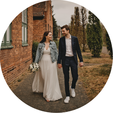 Ein Paar in lockeren Hochzeitsoutfits läuft nach der Trauung im Standesamt Potsdam durch einen Park. 