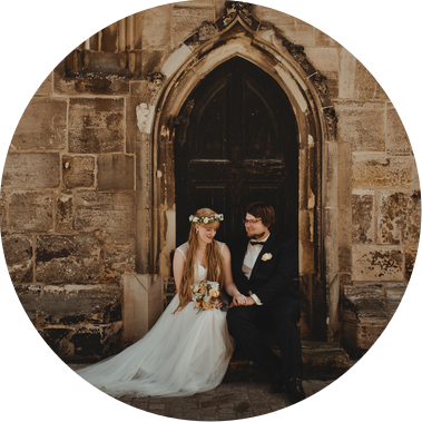 Ein Brautpaar sitzt für Hochzeitsfotos vor dem Portal einer Kirche in Weißenfels. 