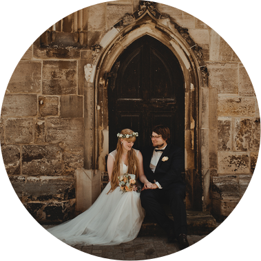 Ein Brautpaar sitzt für Hochzeitsfotos vor dem Portal einer Kirche in Weißenfels. 