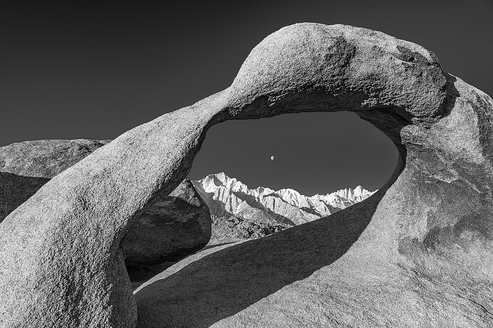 Black and White image of the Mobius Arch and the Eastern Sierra with the moon in the arch.