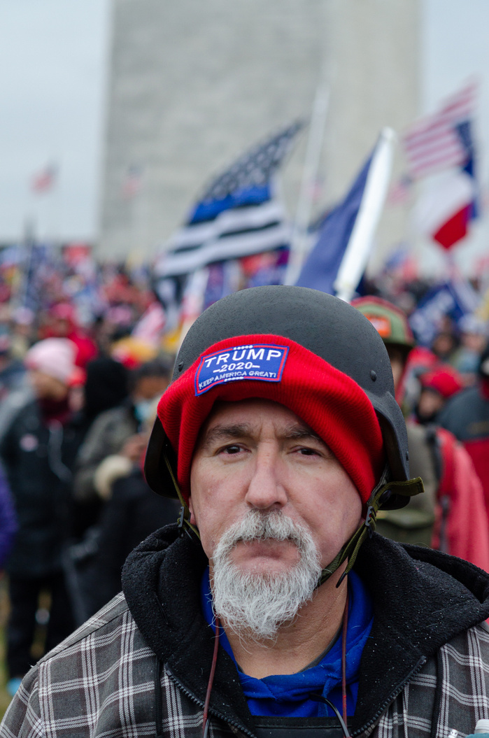 A man wearing a helmet and a hat with a Trump sign
