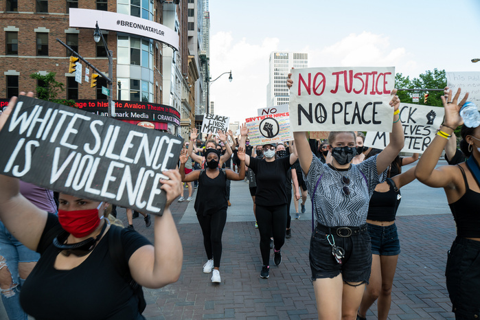 Women dressed in black march and carry protest signs during Black Lives Matter protest