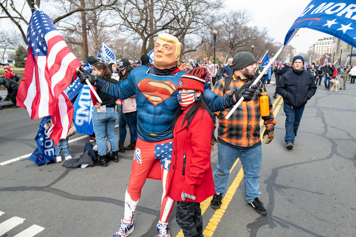 A woman posing for a photo with a man wearing Trump mask at a pro-Trump rally