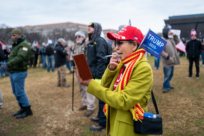 An elderly Asian woman smoking at a pro-Trump rally