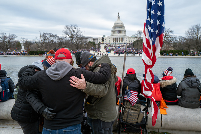 A group of people praying in front of the United States Capitol at a pro-Trump rally