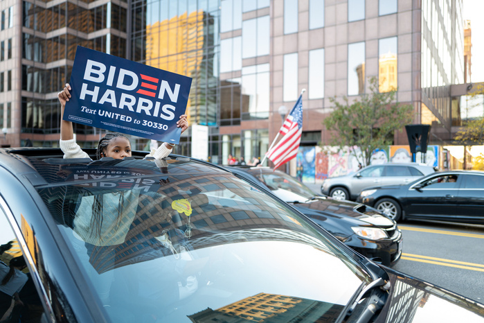 A little girl holding a Biden Harris sign out of a sun roof of a car during the celebration of Biden victory in the 2020 United States presidential election