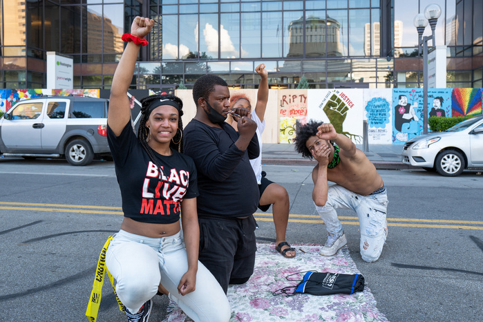 Young people raising fists on a street during the celebration of Biden victory in the 2020 United States presidential election, Black Lives Matter art murals in the background