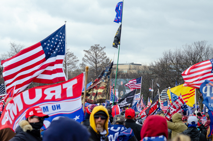 Trump gives speech on big screen surrounded by supporters holding American flags