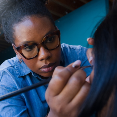 Shaharlee Blake is hard at work applying eye liner with precision and deep focus.