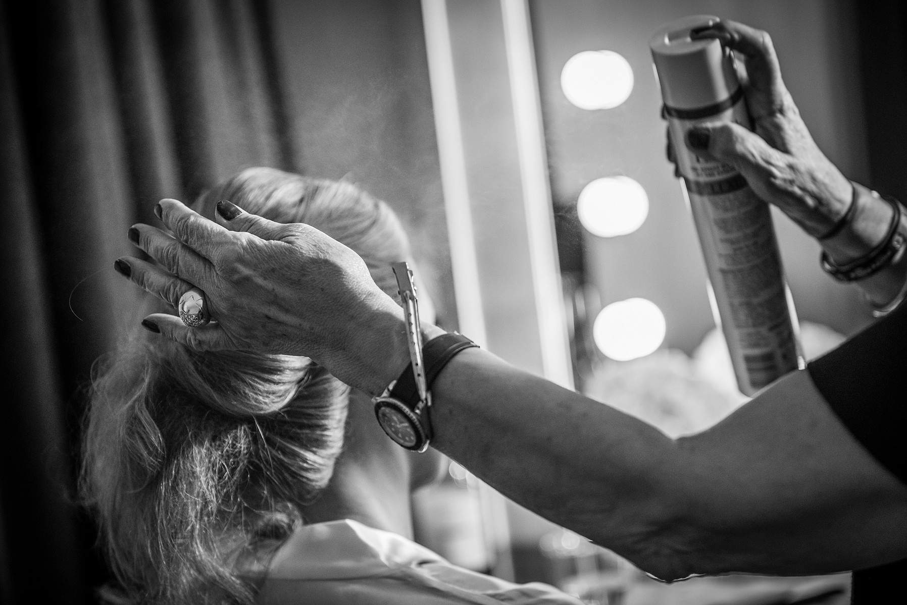 A woman having her hair done by a professional hair stylist in preparation for her portrait session in Vancouver