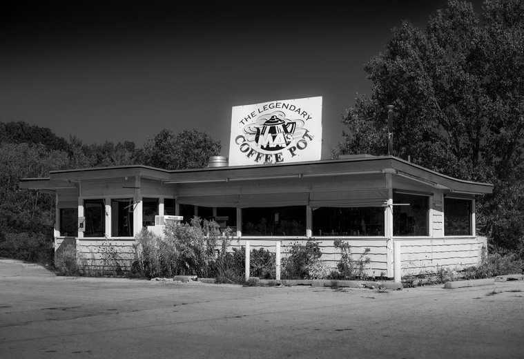An abandoned roadside diner in South Haven, Michigan, “The Legendary Ma's Coffee Pot” sits quietly among overgrown weeds and cracked pavement—its faded sign and vacant windows echoing the charm and nostalgia of a once-beloved local landmark.