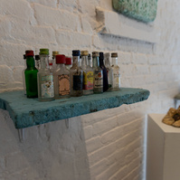 From Priscilla Stadler's SLUDGE art project about a toxic NYC waterway. Image shows used nips (mini liquor bottles) mounted on a weathered piece of light blue styrofoam, all found at the Creek.