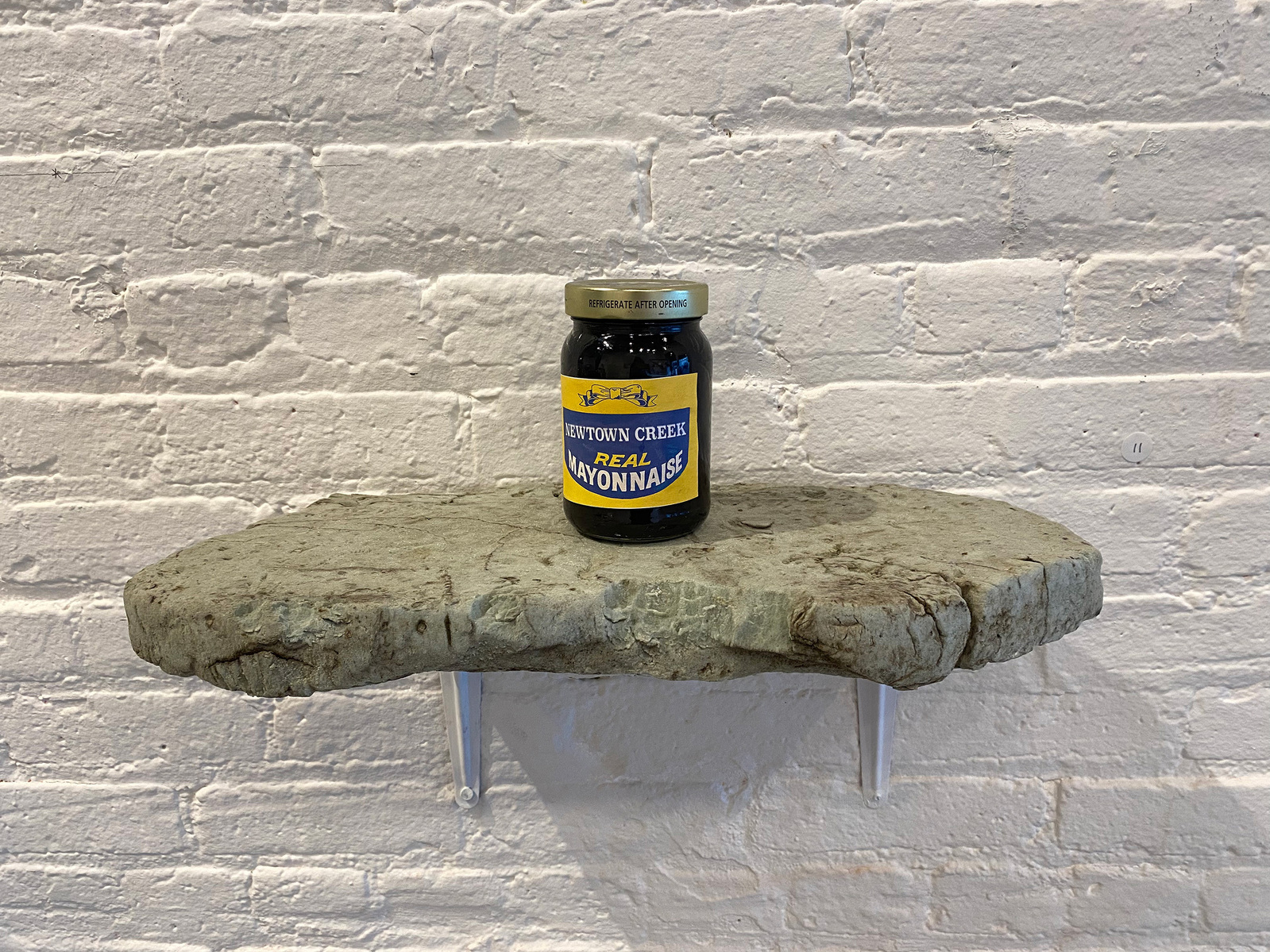 From Priscilla Stadler's SLUDGE art project about a toxic NYC waterway. Image shows a jar labeled: "Newtown  Creek Mayonnaise" - with black material inside. The Creek's contaminated sediment is called "black mayonnaise".