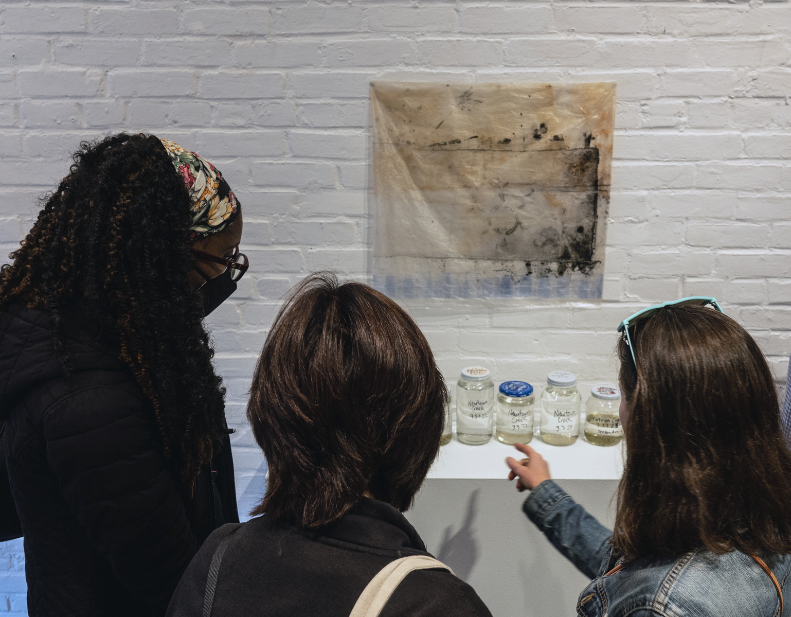 Visitors look at "Samples" and "Troubled Waters 11", works from Priscilla Stadler's SLUDGE project, an art installation created in response to researching Newtown Creek, a toxic waterway dividing Queens & Brooklyn, NYC.