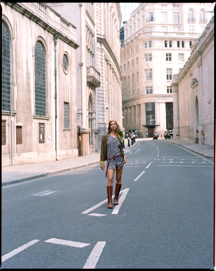 Wide shot of Larissa Diniz wearing vintage dress and and head wrap in Lothbury in City of London