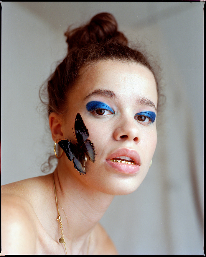 Medium close-up beauty shot of Anna Oloyede in beauty shot with butterfly on her cheek