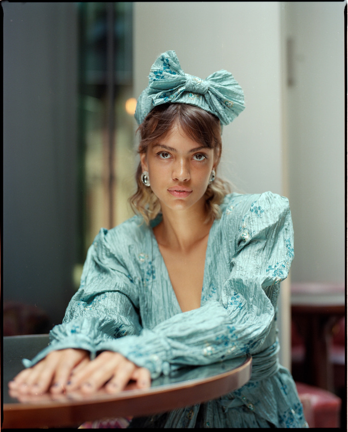 Larissa Diniz sat at a cafe table wearing Paula Nadal outfit