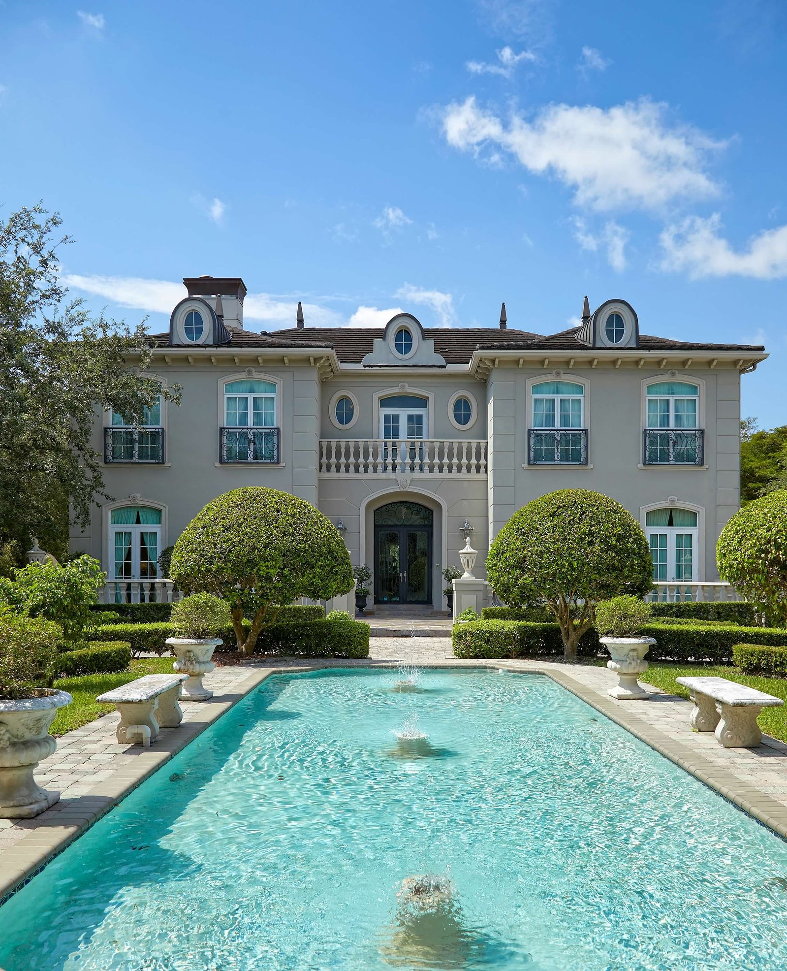 This serene backyard retreat blends classic European charm with lush greenery for the ultimate relaxation