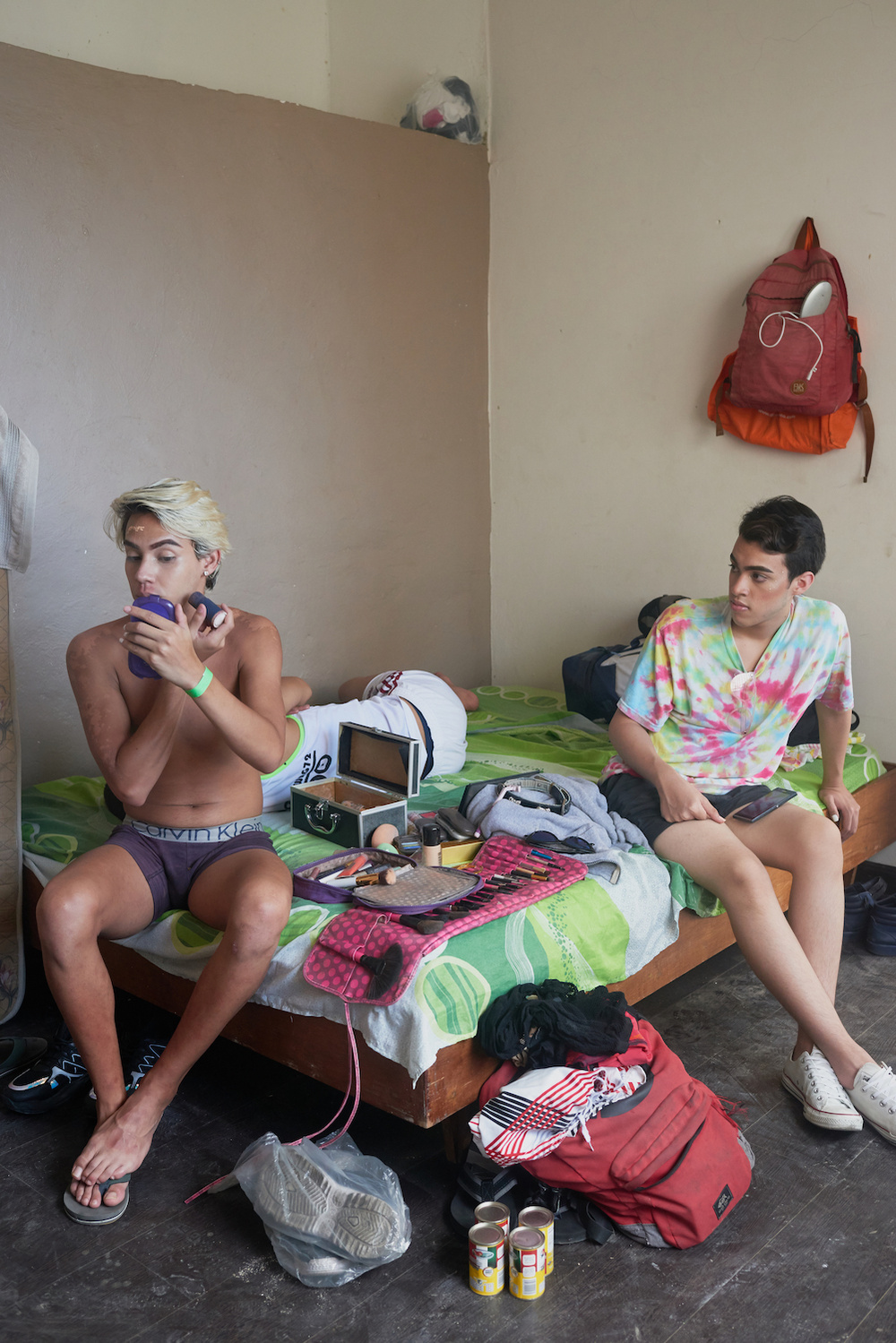 CARACAS - FEBRUARY 24, 2020.
Victor, known as Roxy, and a party bouncer sit in a bedroom/makeshift dressing room while Victor begins putting on his makeup - getting ready for a private LGBTQ beach party.