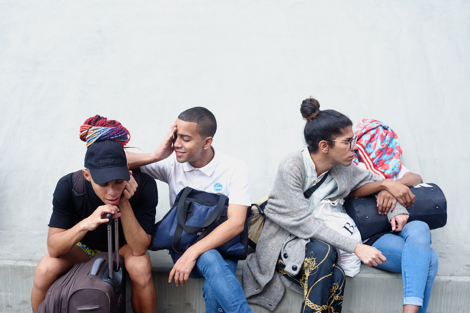 CARACAS - FEBRUARY 24, 2020 A group of drag performers in downtown Caracas, sitting at a bus stop. After spending the night at the club, they left early in the morning for a private beach party. A private bus is taking them t