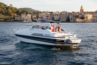 Aerial view from helicopter of a yacht in Saint-Tropez, South of France at sunset with family standing in front on the village.