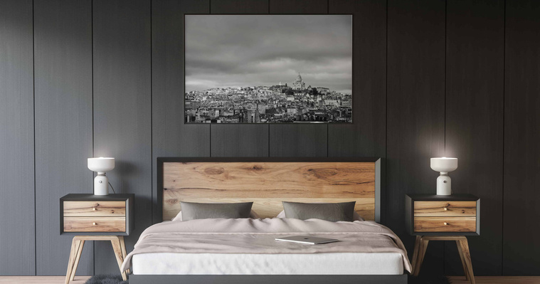Une photographie de Paris en noir et blanc imprimée et encadrée sur un mur noir dans une chambre au-dessus d'un lit.