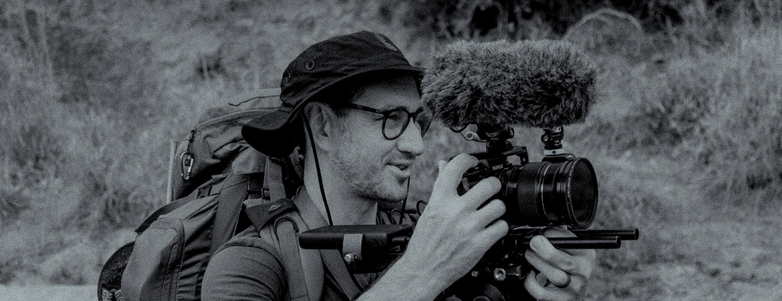 Alex Shapiro director standing with hiking bag and fujifilm xt3 camera filming a project
