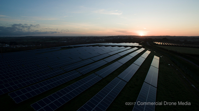 Aerial drone survey and inspection of solar panels. UAV shot of PV system with sunrise in background. Devon.