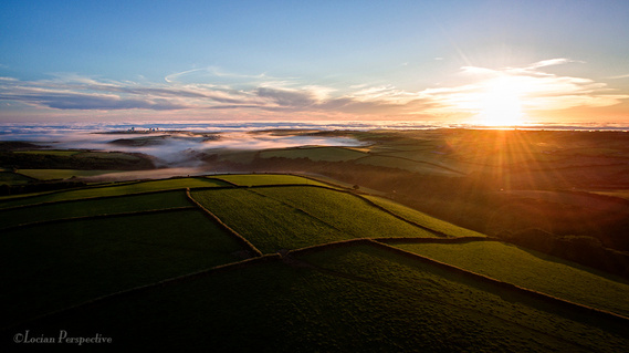 aerial drone image, commercial photograph of sunset over Cornwall with low level, coastal sea mist. UAV_Cornwall.