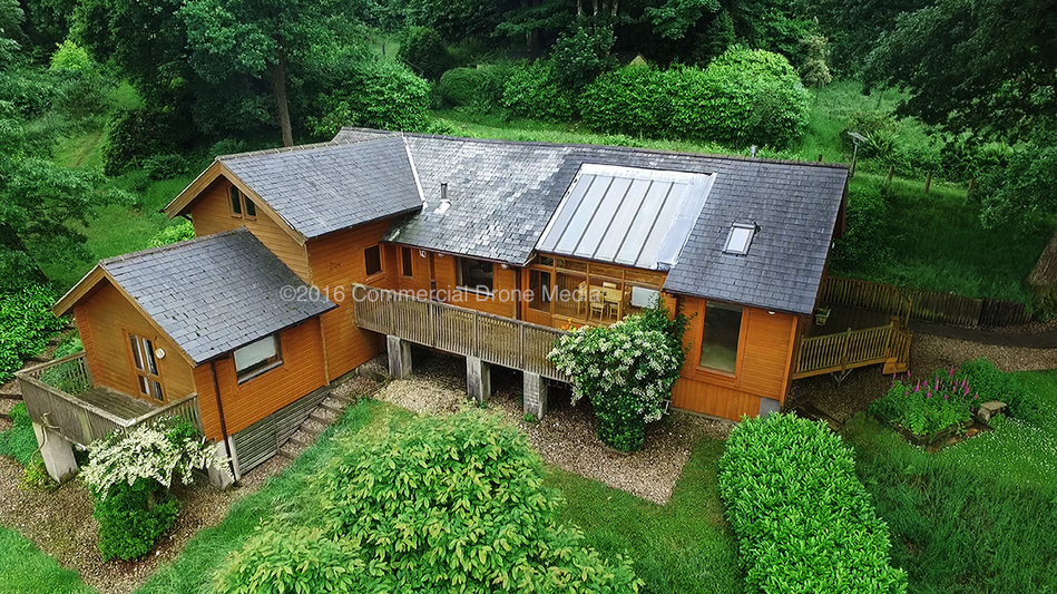 Commercial drone property photography. Aerial drone image, UAV photograph of Devon property for estate agent, real estate, property sale. Norwegian log cabin style house.