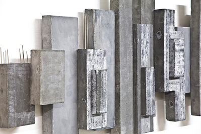 A detail of an architectonic cubic sculpture made of cast concrete with dark pigment. Stainless steel is part of the construction.
