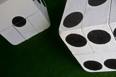 A detail of a sculpture made of modified breeze blocks on artificial turf to resemble dice painted white with black spots painted with tar.