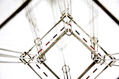 An architectonic cage-like frame sculpture made of stainless steel.