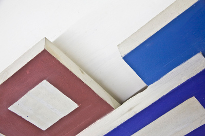A cluster of architectonic cubic sculptural parts made of cast concrete with some painted surfaces.
