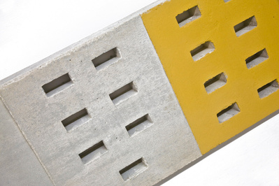 A row of architectonic cubic sculptural parts made of cast concrete with some painted surfaces.