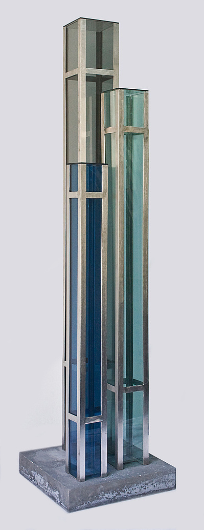 An architectonic cubic sculpture made of blue, green and brown glass and stainless steel.