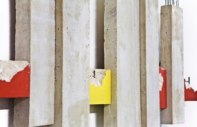 A detail of an architectonic cubic sculpture made of cast concrete with smashed parts. Mild steel is part of the construction.