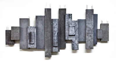 A monochromatic architectonic cubic sculpture made of cast concrete with dark pigment. Stainless steel is part of the construction.