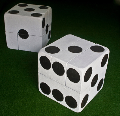 A sculpture made of modified breeze blocks on artificial turf to resemble dice painted white with black spots painted with tar.