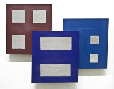 A cluster of architectonic cubic sculptural parts made of cast concrete with some painted surfaces.
