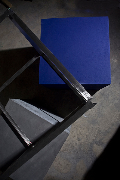A detail of a sculpture made of 3 cubes: a cube made of stainless steel frame, a cube made of cast concrete and a cube painted purple