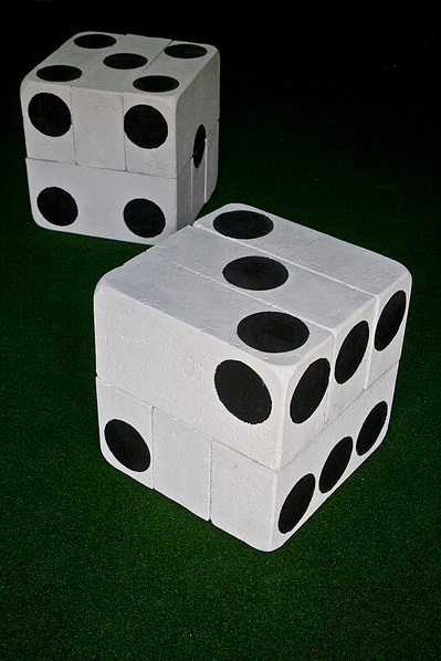 A sculpture made of modified breeze blocks on artificial turf to resemble dice painted white with black spots painted with tar.