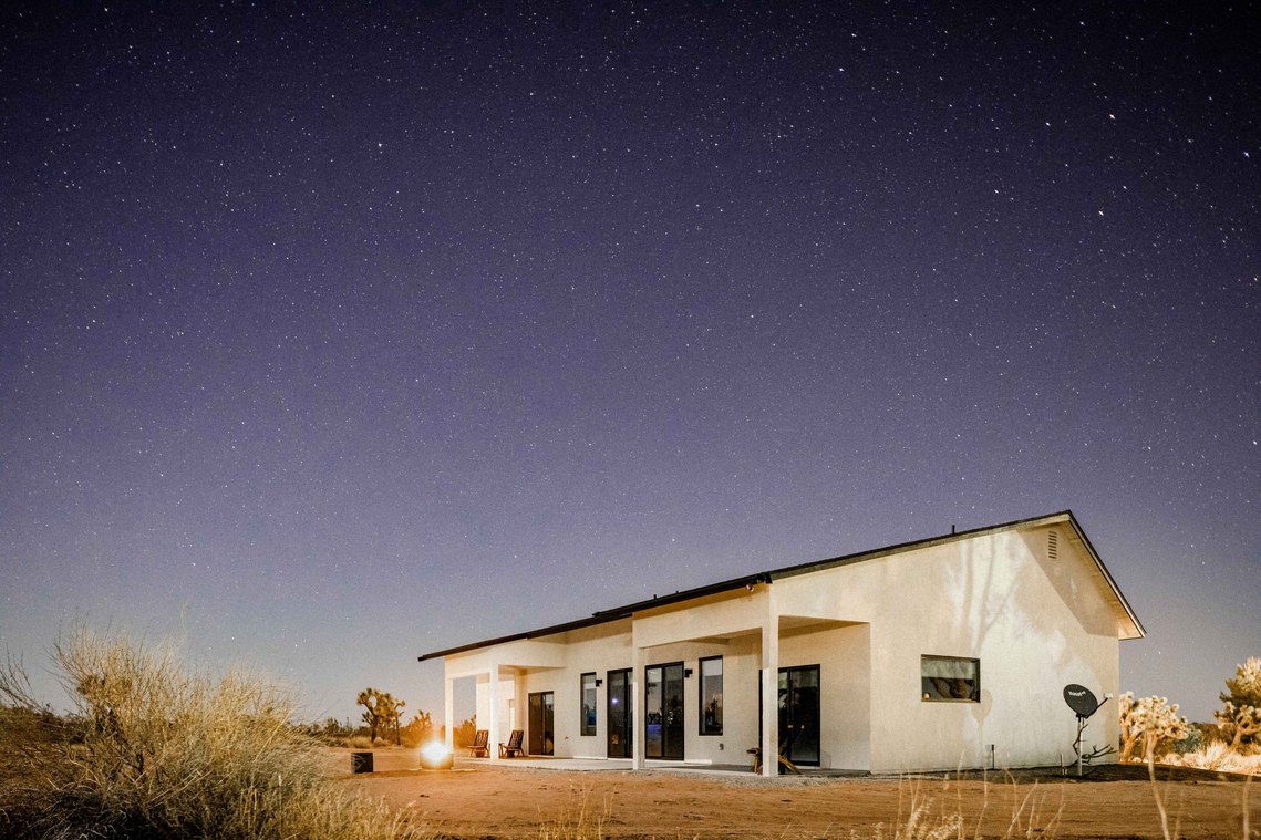 White stucco home in desert under night  sky full of stars 