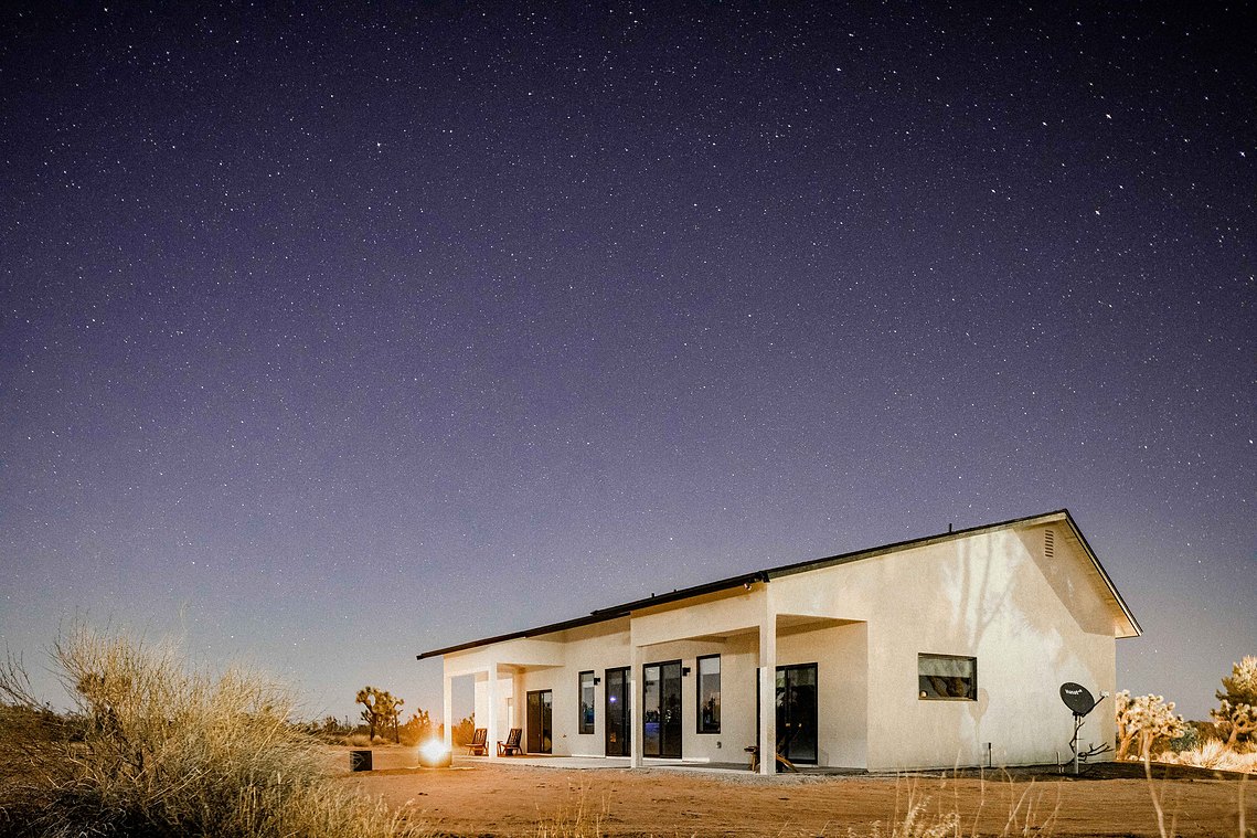 White stucco home in desert under night  sky full of stars 
