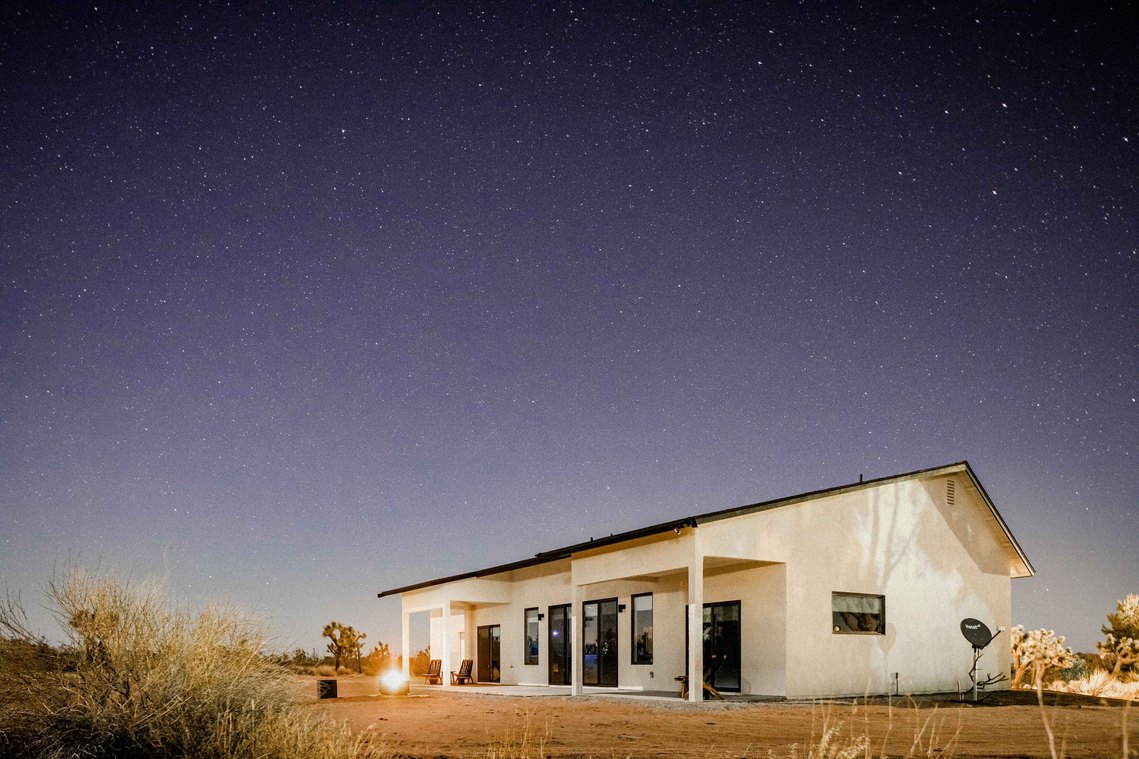 White stucco home in desert under night  sky full of stars 