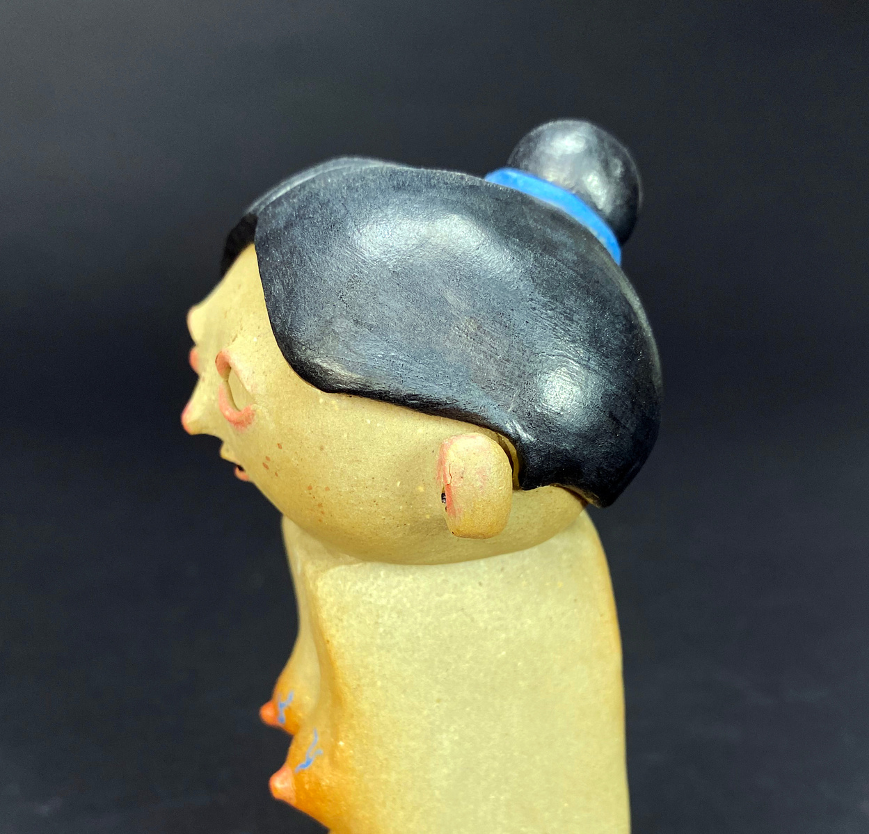 A small ceramic figure bust. A pregnant woman with blue veins trailing her stomach and breast. her mouth is slightly agape, and her black hair is in a bun with a blue scrunchie.