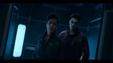 2 Actors stand inside an elevator. Details inside include decorative panels, lighting and lighting bevels and handholds. 