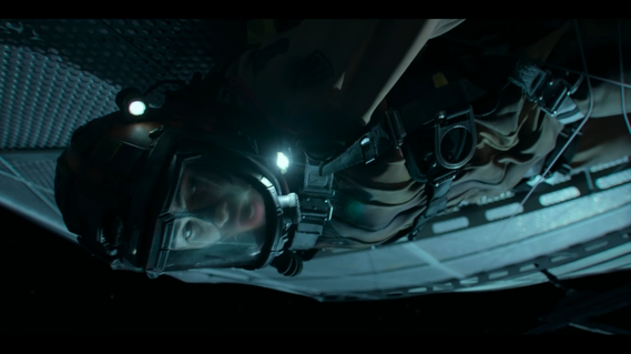 Actor lies on the underside of a giant satellite. It is made of perforated metal sections layered atop each other.